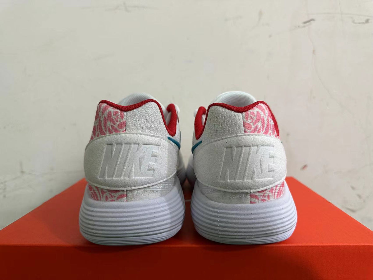 Rear view of white Nike sneakers with pink patterned heel panels, red trim, and ridged soles.