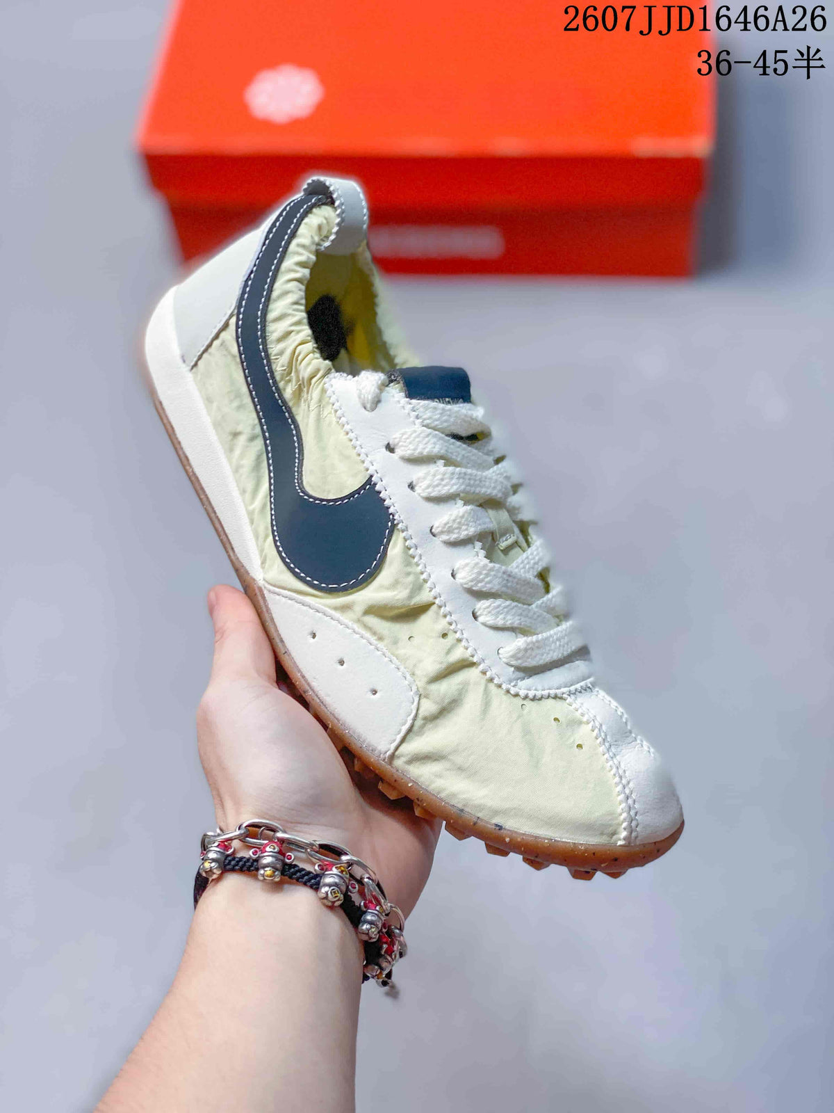 Angled side view showing the dark navy Swoosh, cream upper, white heel area, and gum-colored outsole.