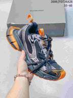 Dark gray Balenciaga 3XL-style sneaker with orange accents