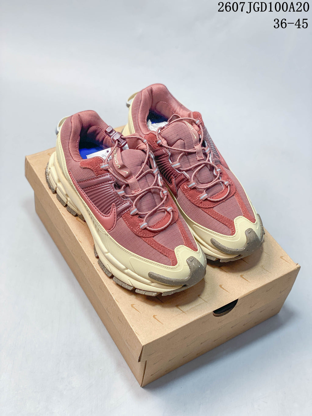 Pair of burgundy and cream Nike Zoom Vomero Roam sneakers displayed on a shoebox; style code 2607TGD100A20 and size range 36–45 appear at the top.