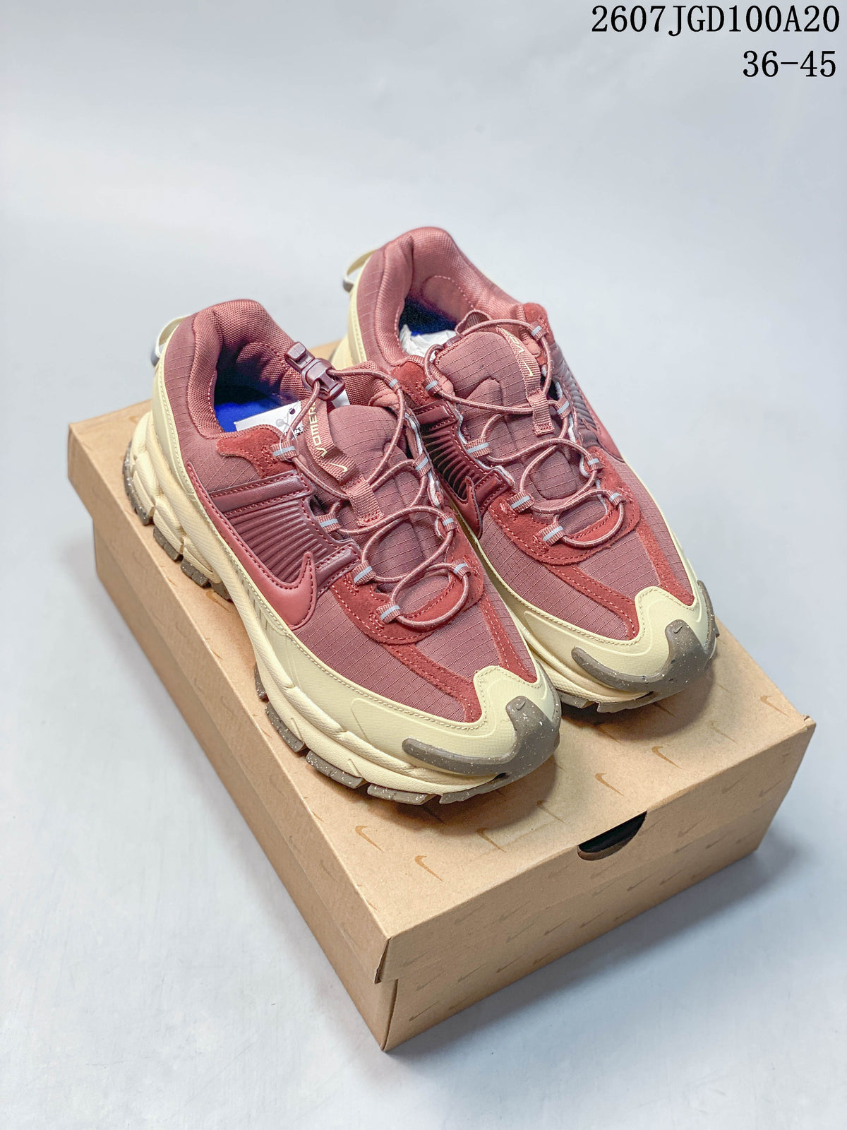 Pair of burgundy and cream Nike Zoom Vomero Roam sneakers displayed on a shoebox; style code 2607TGD100A20 and size range 36–45 appear at the top.