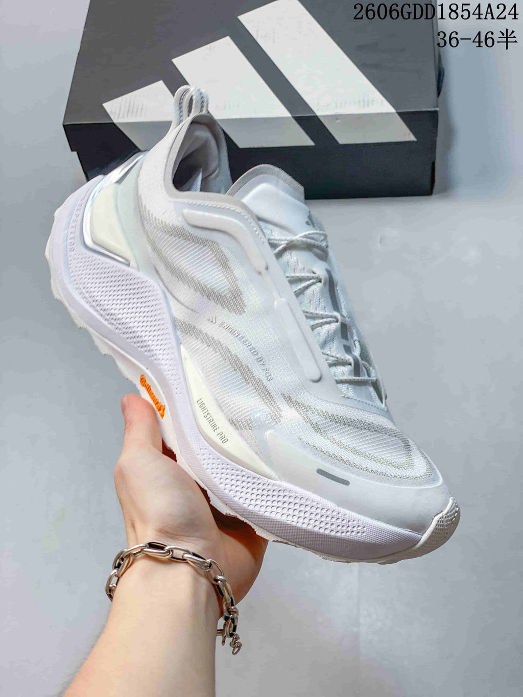 Angled side view of a white and light-gray trail-running shoe