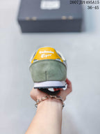 Rear view of a green Onitsuka Tiger Serrano sneaker with a yellow heel accent, white midsole, and dark outsole.