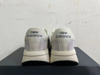 Rear view of gray and off-white New Balance U370 sneakers with navy heel branding.
