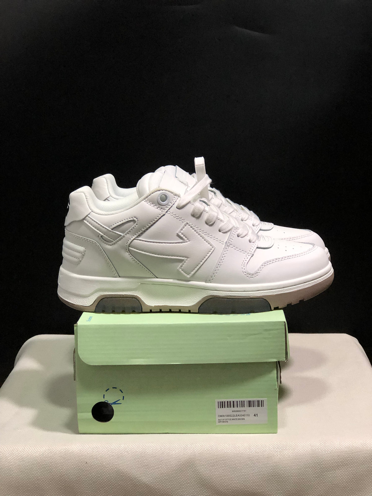 Side view of a white low-top sneaker showing layered side panels, padded collar and segmented outsole.