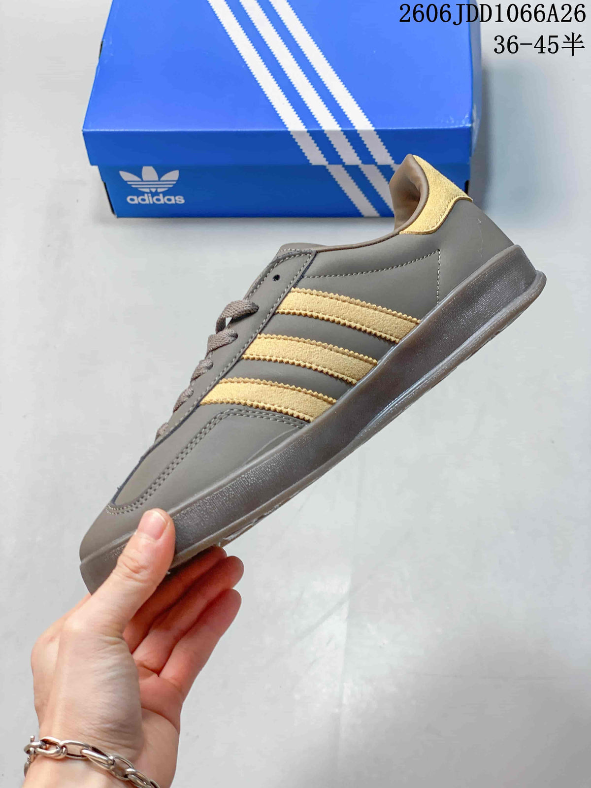 Side profile highlighting the gray upper, three gold-toned stripes, low-top silhouette, and flat outsole.