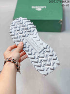 Close view of the textured white lugged outsole of the Lacoste sneaker, with the green shoe box in the background.