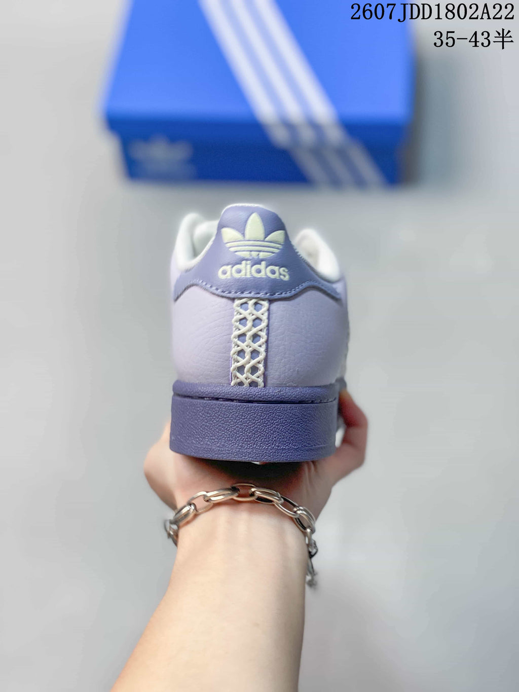 Rear view of a lavender Adidas Superstar sneaker with white collar padding and heel branding.