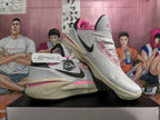 Pair of white basketball shoes with pink and black accents, shown from the side