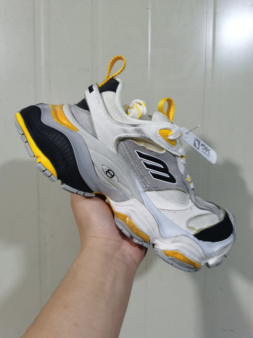 Close-up angled view of grey, black, and yellow 1170 sneakers with layered panels and contrast outsole accents.