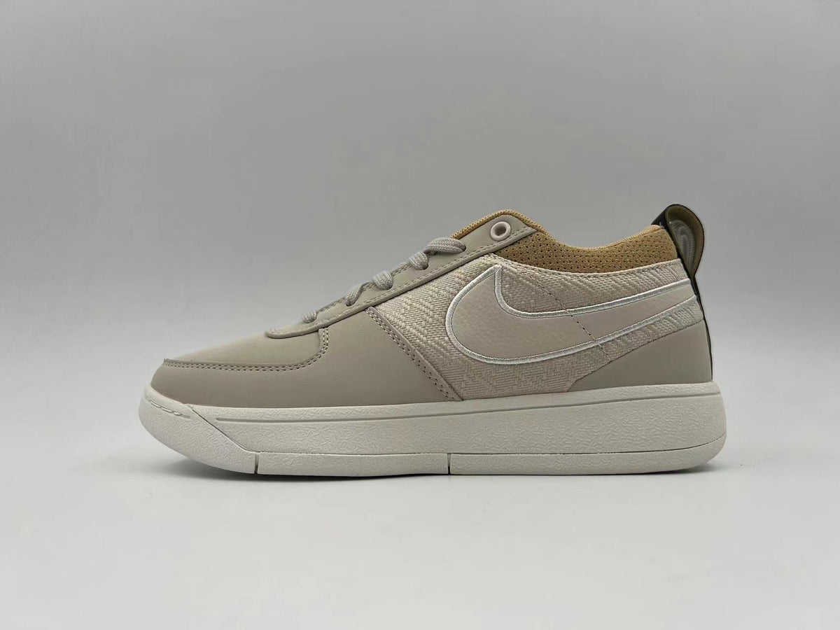 Side view of an off-white Nike low-top sneaker with a tonal Swoosh and textured side panel