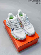 Pair of white Nike Air Pegasus Premium sneakers with blue accents and green cushioning units on an orange shoebox.