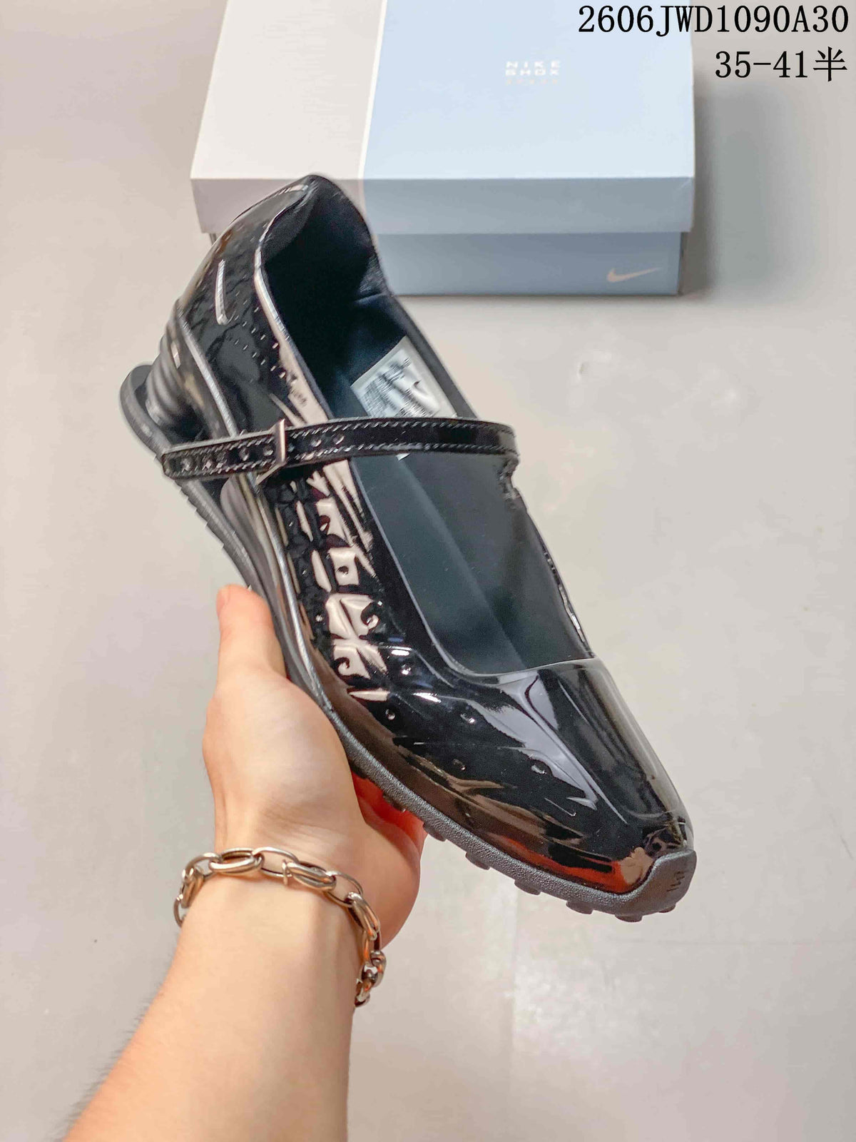 Angled view of the glossy black Mary Jane-style shoe and adjustable strap