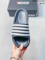 Top view of the dark slide sandal showing the open toe, textured footbed, and four white bands.