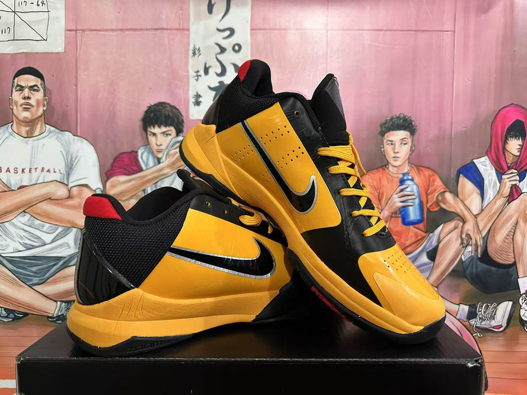 Pair of yellow and black Nike basketball shoes with red accents