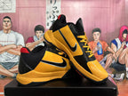 Pair of yellow and black Nike basketball shoes with red accents
