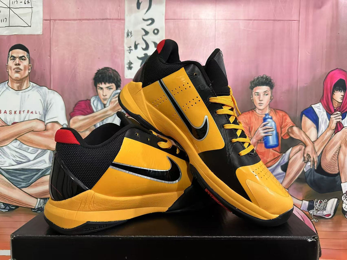 Pair of yellow and black Nike basketball shoes with red accents