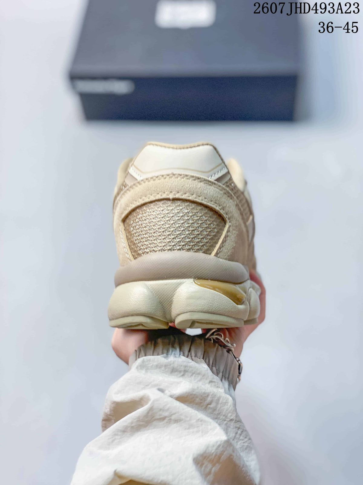 Rear view showing the padded heel and sculpted outsole of the beige and cream sneaker.