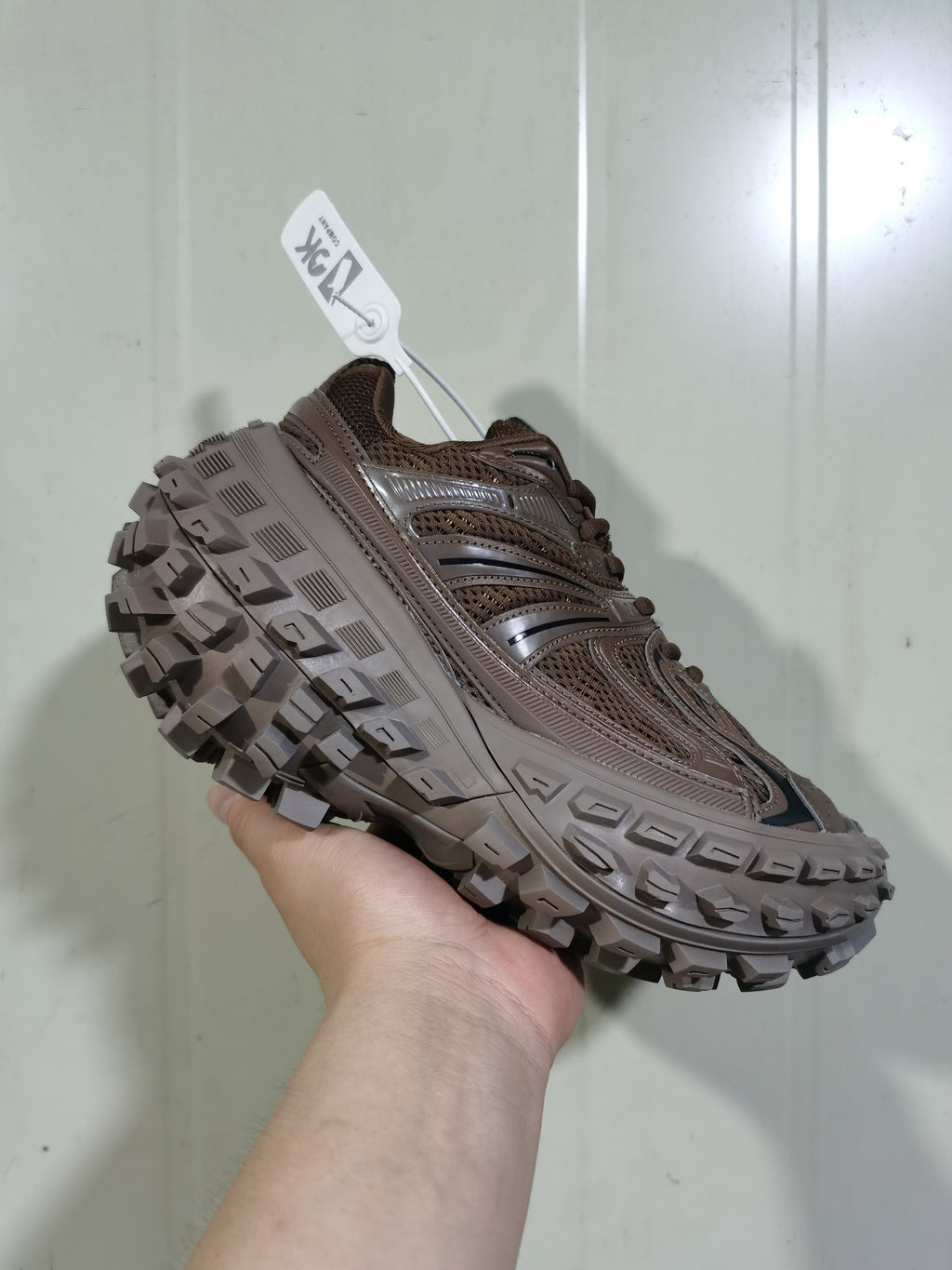 Angled front-side view of the coffee-brown sneaker highlighting its layered upper, padded collar, and deep outsole tread.
