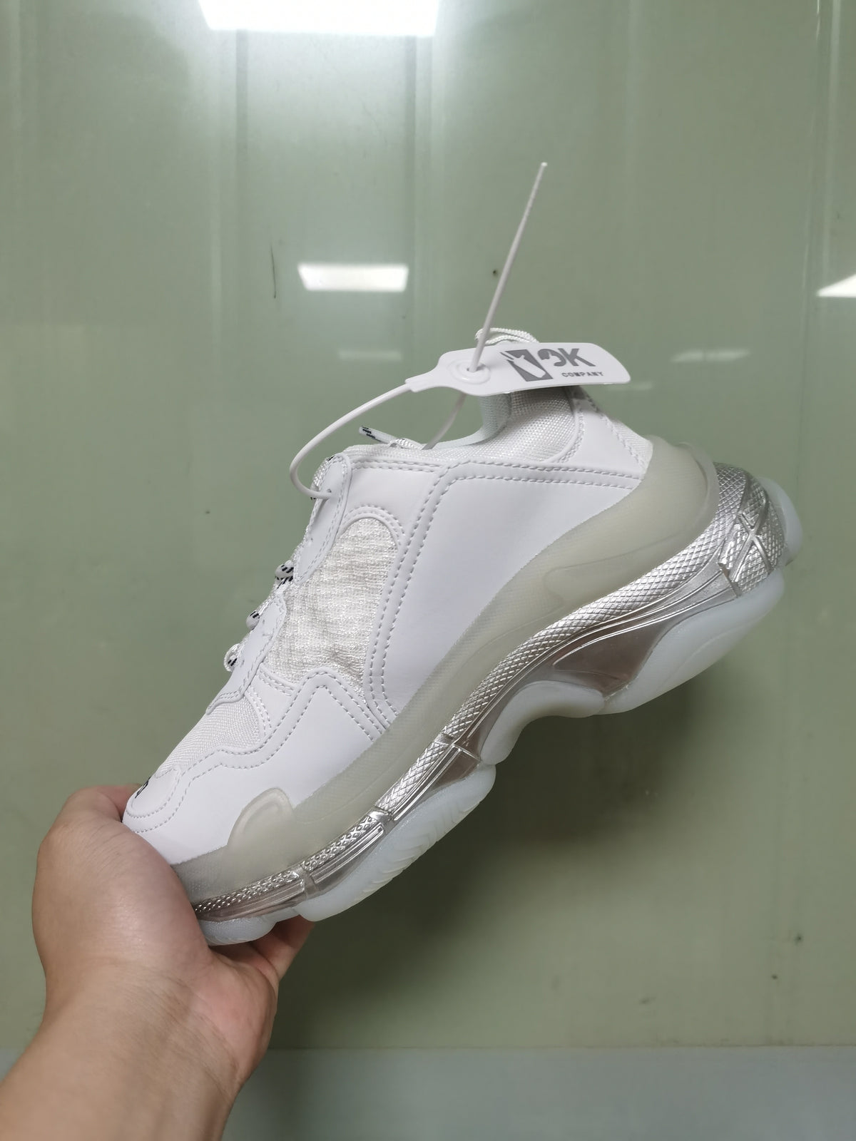 Angled rear-side view of the white Balenciaga sneaker showing the layered upper, translucent outsole sections, and iridescent sole detailing.