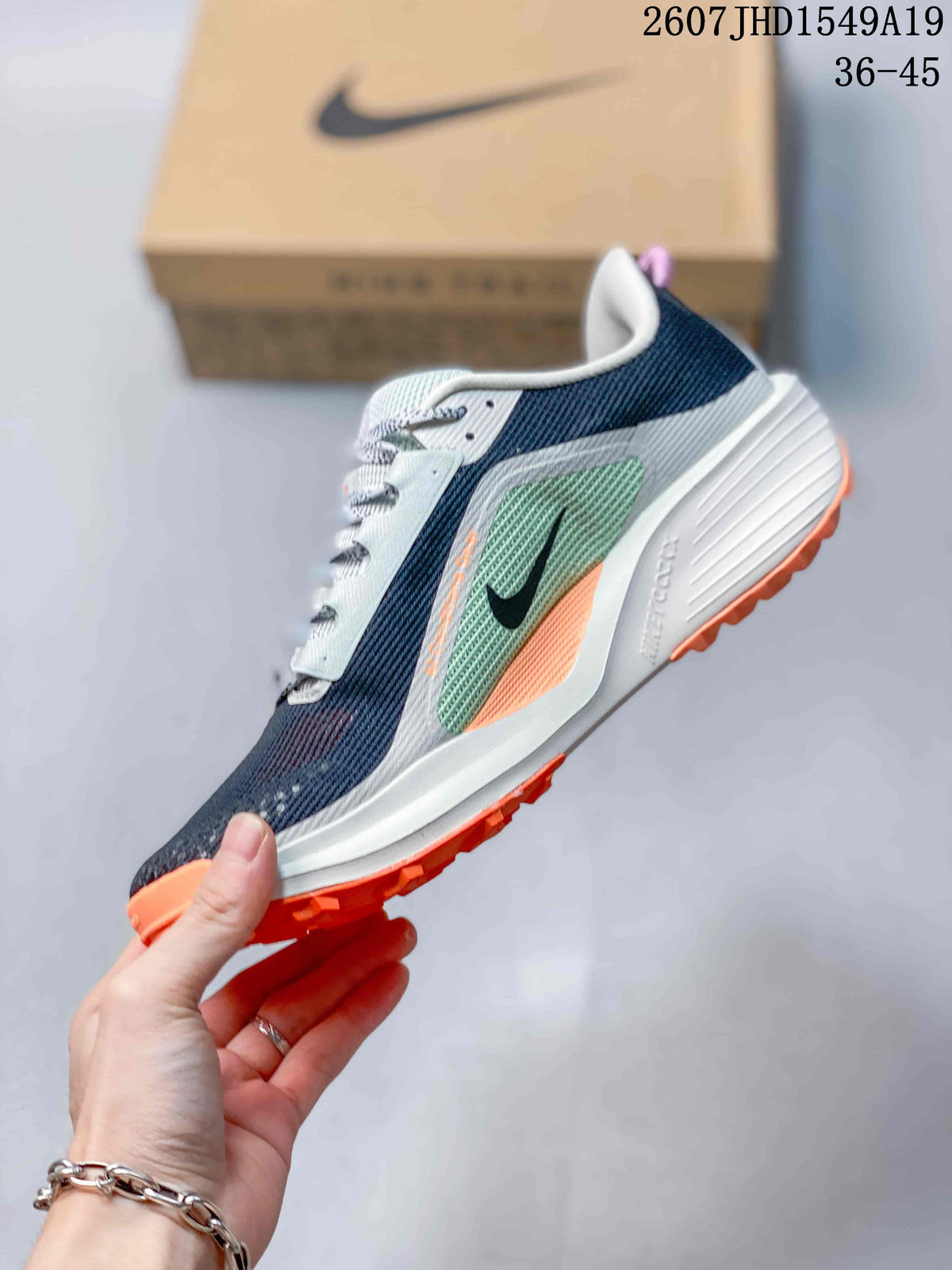 Side profile showing the navy upper, mint-green panel, black Swoosh, white midsole and orange outsole accents.