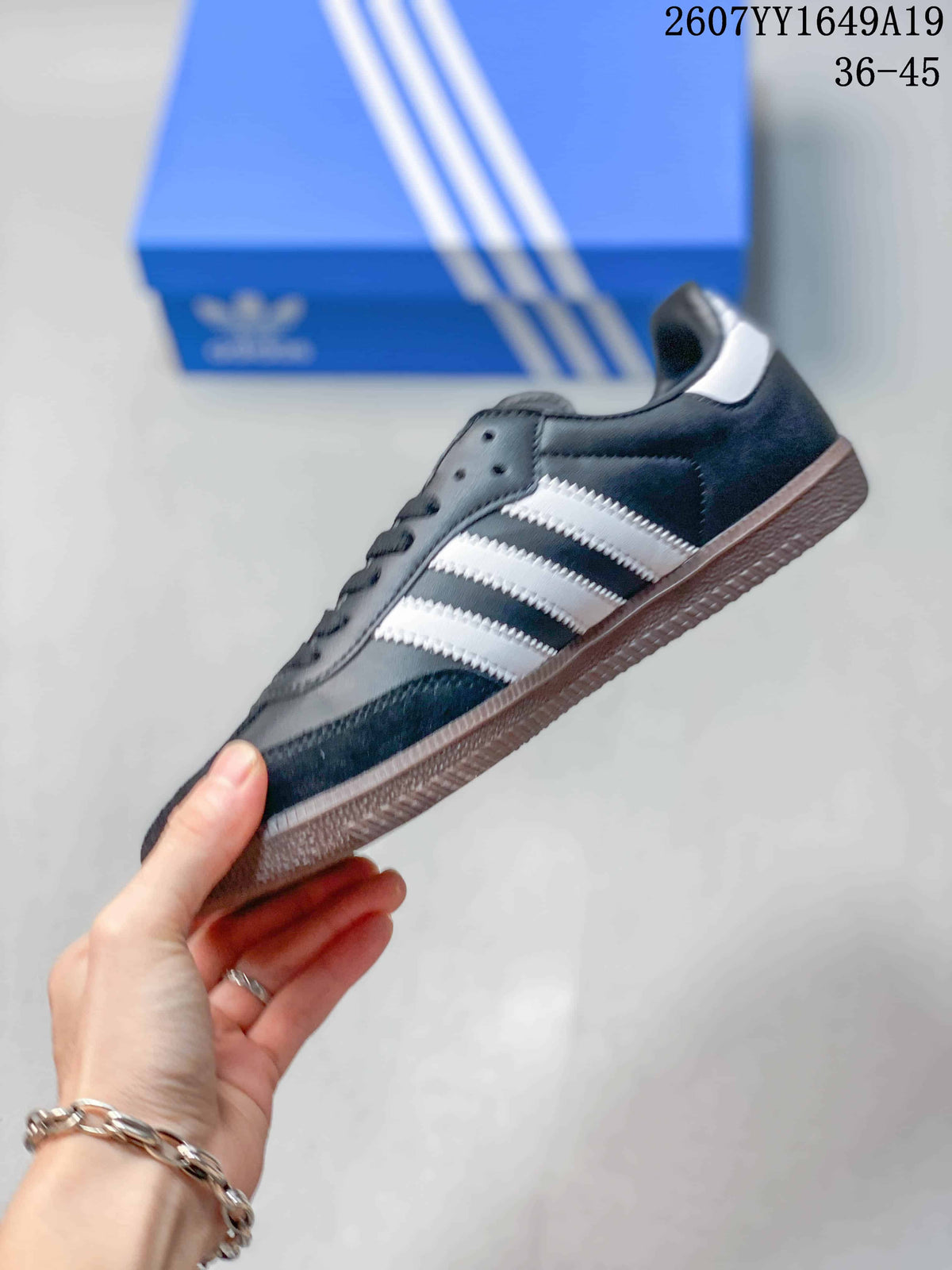Side profile of the black low-top sneaker showing white three-stripe detailing, a gum sole and low-profile silhouette.