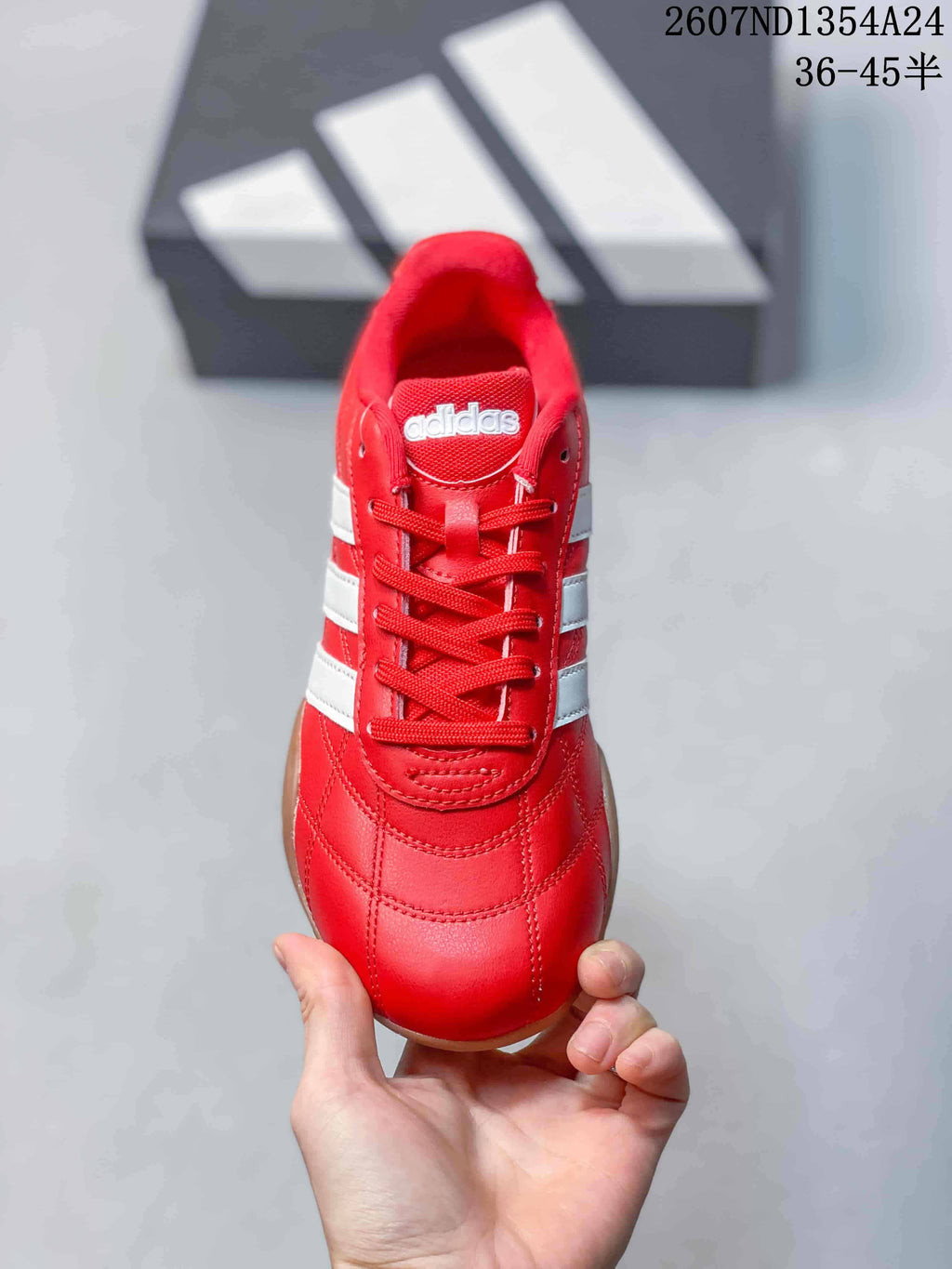 Top view of the red lace-up sneaker showing the tongue, eyelets, stitching, and white side stripes.