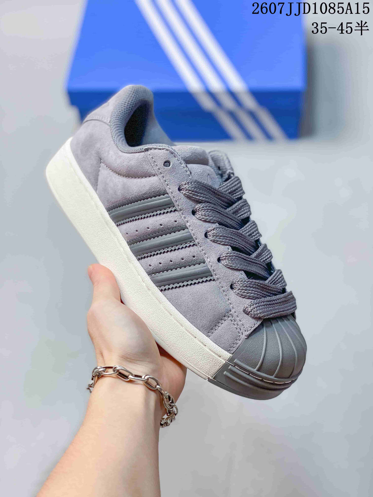 Side view of a gray adidas shell-toe sneaker with gray laces and a light-colored sole.