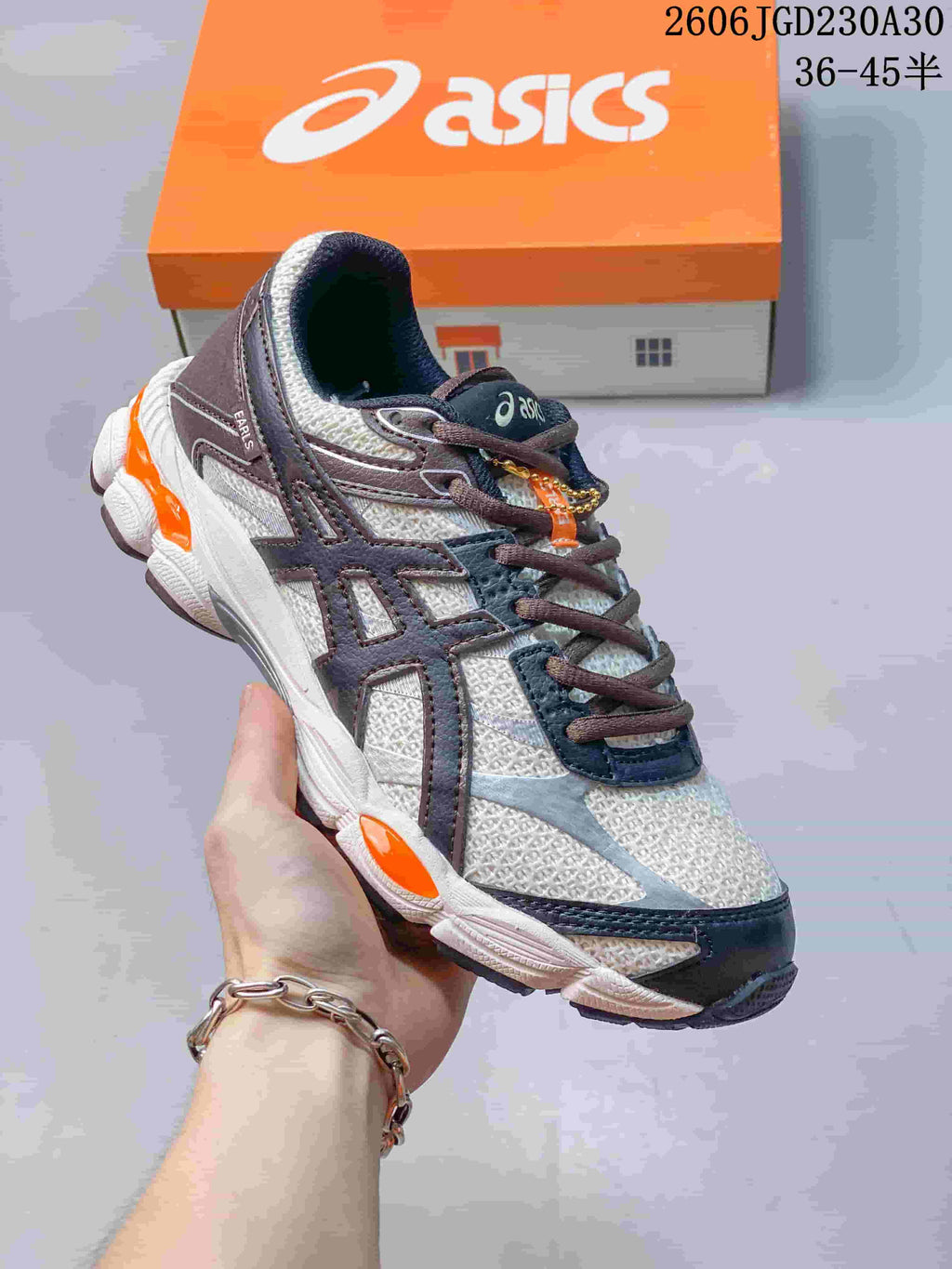 Angled close view of an ASICS GEL-CUMULUS 16 shoe with dark overlays and orange details.
