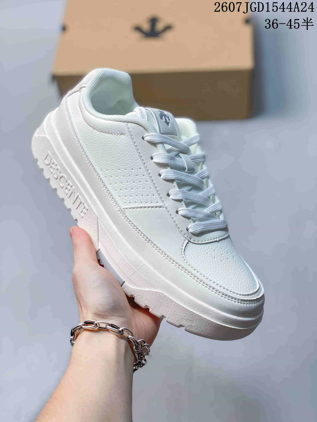 Angled side view of the white DESCENTE sneaker showing the layered upper and outsole lettering.