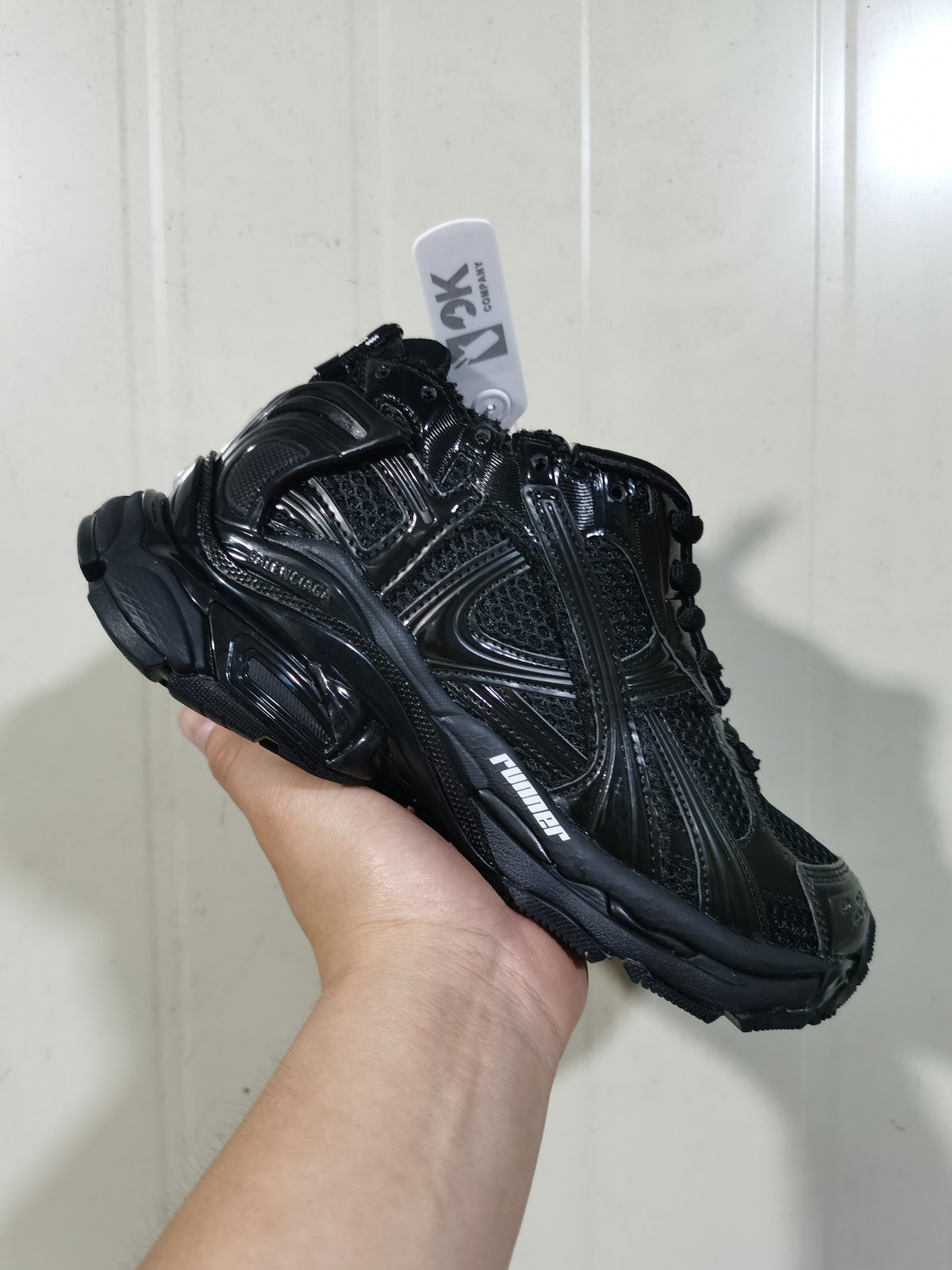 Close angled view of the black Balenciaga Runner sneaker showing layered side panels, lace-up construction, and Runner branding.