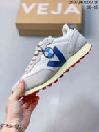 Side view of the white and blue sneaker showing the blue V logo, mesh-style panel, light overlays, cream midsole, and red outsole.