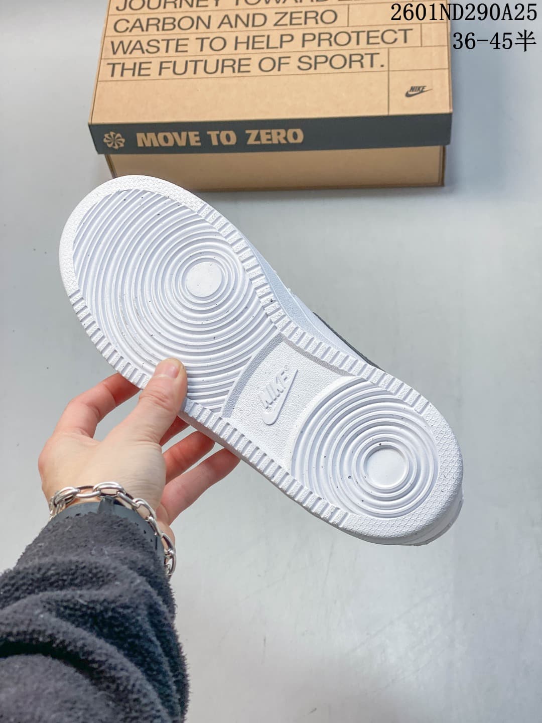 White sneaker outsole showing circular traction grooves and Nike branding, with the box behind it.
