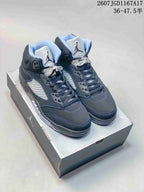 Pair of black Jordan Air Jordan 5 high-top sneakers displayed on a shoebox, showing blue-gray stitching, padded collars and translucent outsoles.
