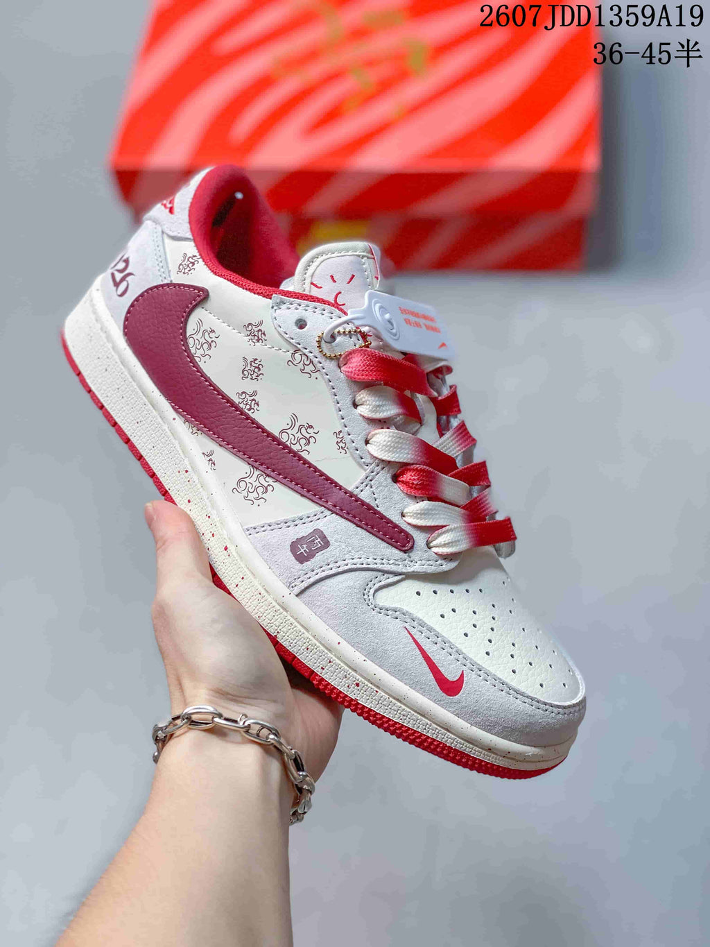 White and burgundy low-top sneaker with printed panels, burgundy accents, red laces, and a red outsole.