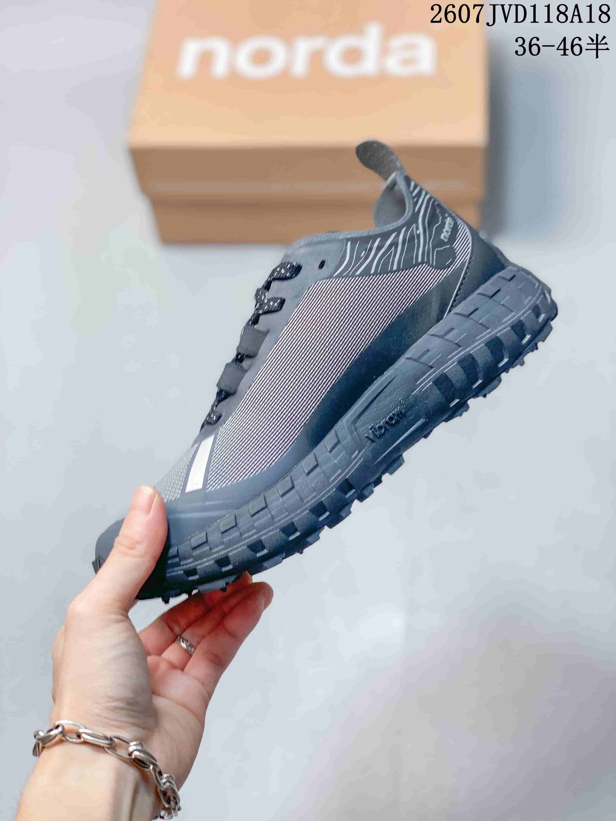 Side profile of the gray Norda sneaker showing the patterned upper, lace system, layered midsole, and lugged outsole.