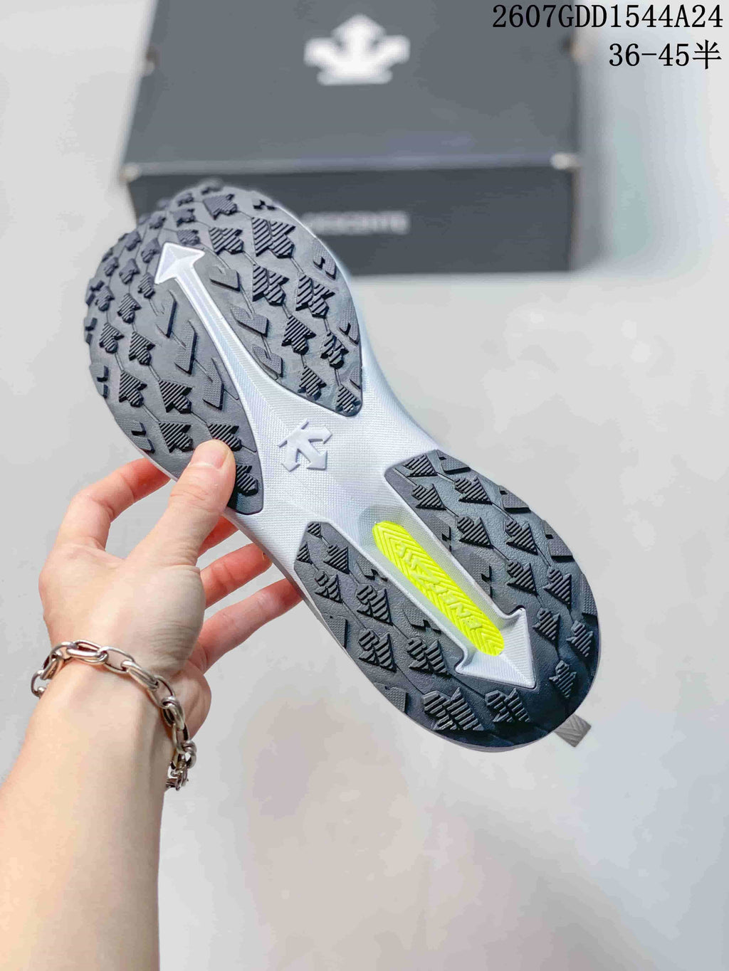 Close view of the sneaker outsole showing a gray base, black directional tread sections, and a bright yellow insert.
