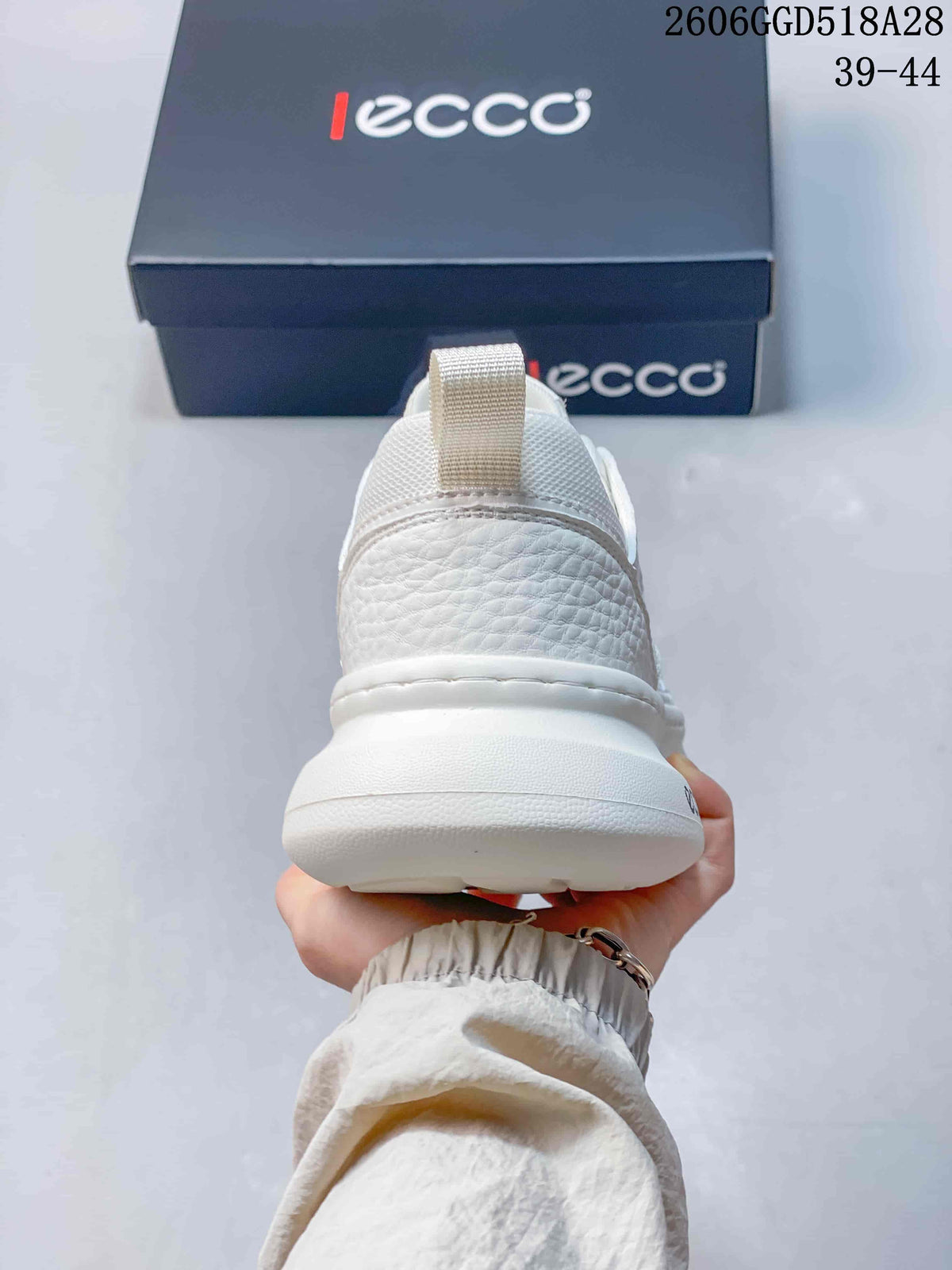 Rear view of the white sneaker with textured heel panel and thick sole.