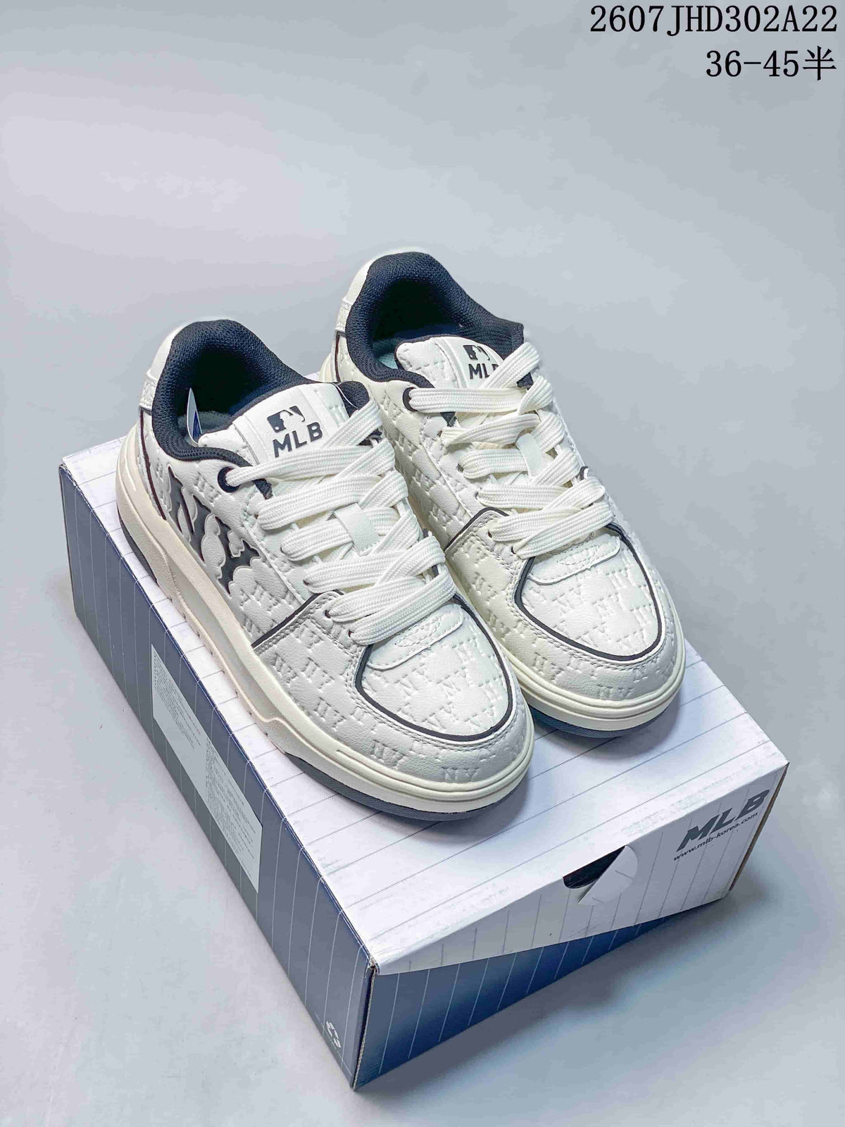 Pair of white and navy MLB sneakers displayed on a branded shoe box, showing the chunky sole and textured upper.
