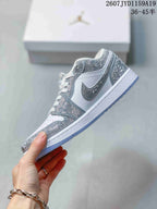Side profile of a white low-top sneaker with silver decorative overlays, swoosh detail, white midsole, and translucent outsole.