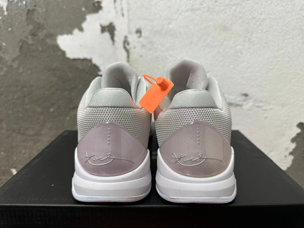Rear view of silver and white Kobe basketball shoes with signature heel details.