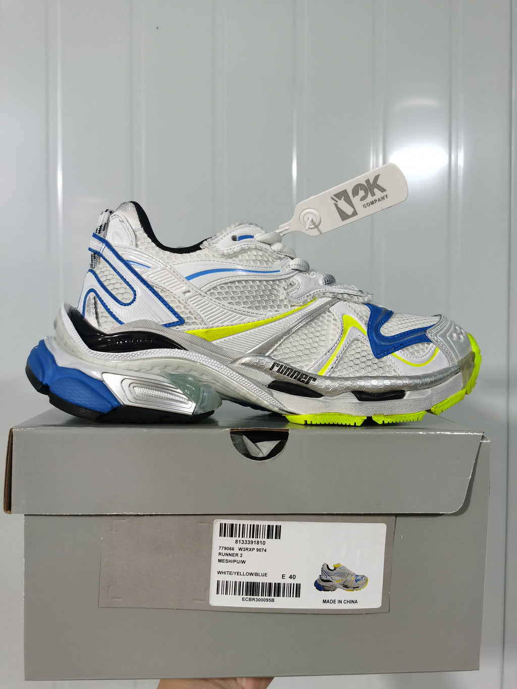 White, blue and yellow Nike 9074 Runner 2 sneaker displayed on its box; the box label shows size E 40.