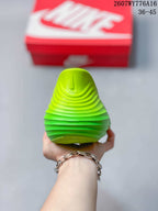 Rear view showing the raised heel structure and layered sole of the neon green clog.