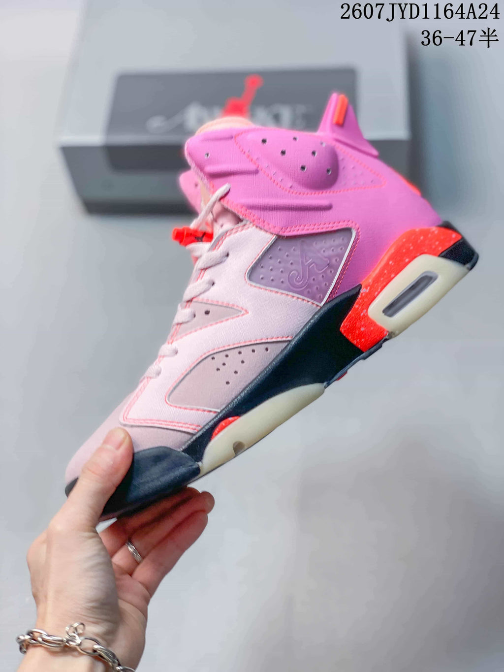 Side profile of the pink high-top sneaker showing perforated panels, stitched overlays, black sections, red accents and visible heel cushioning.