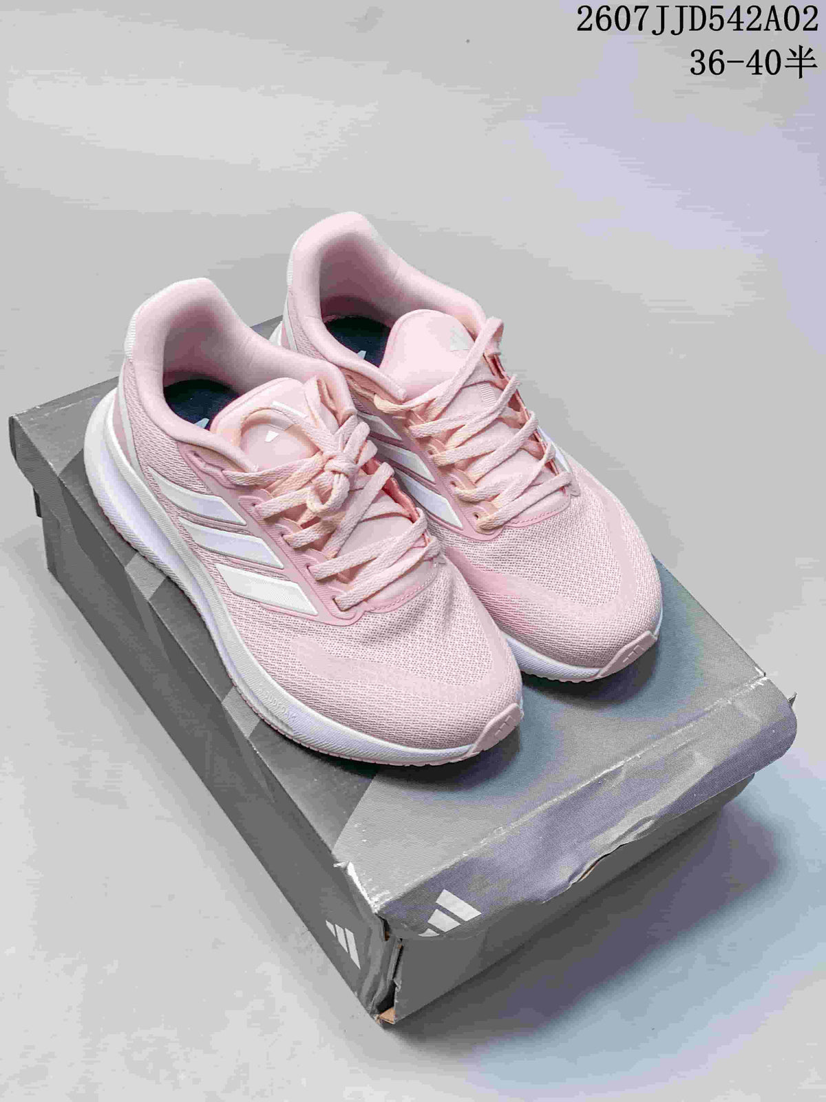 Pair of pink Adidas Runfalcon 5 shoes on a shoebox, viewed from above.