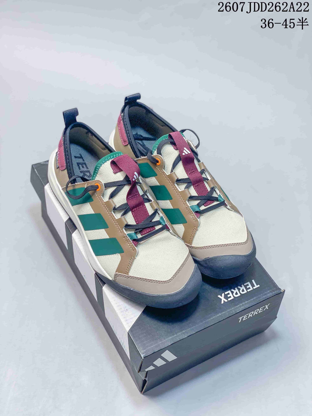 Pair of adidas Terrex hiking shoes in beige, green, burgundy and navy displayed on a Terrex shoebox.