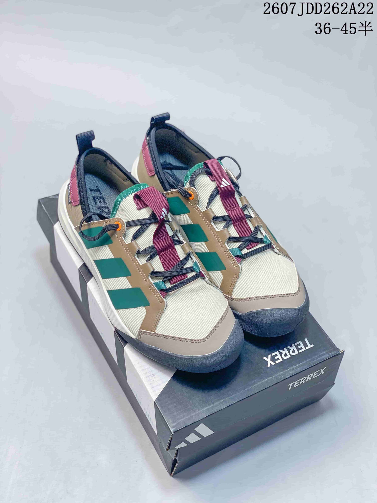 Pair of adidas Terrex hiking shoes in beige, green, burgundy and navy displayed on a Terrex shoebox.