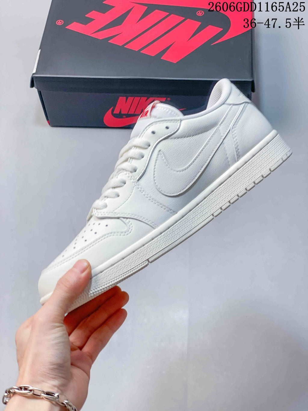 Side profile of the white low-top sneaker with a white side logo and red tongue detail.