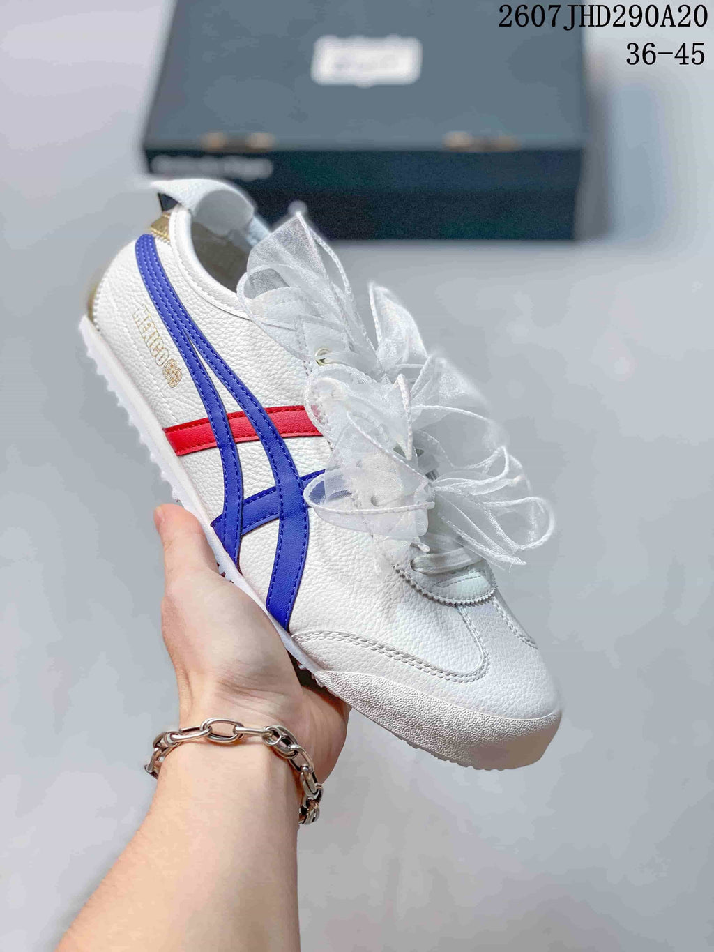 White low-top sneaker with blue and red side stripes and translucent ribbon laces.