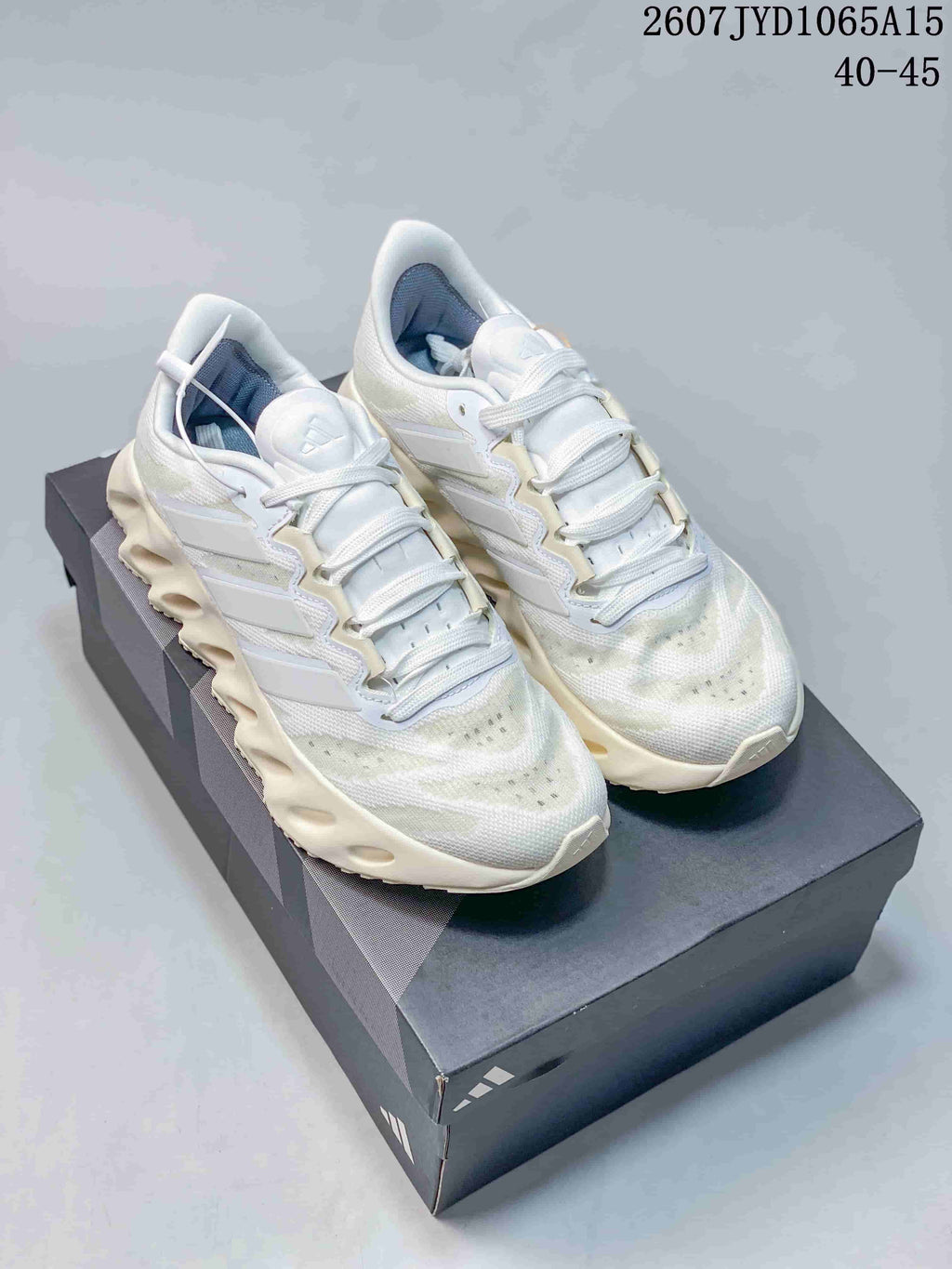 Pair of white Adidas Alphabounce Switch sneakers displayed on a shoebox, with style code JYD1065A15 and size range 40–45 visible at the top.
